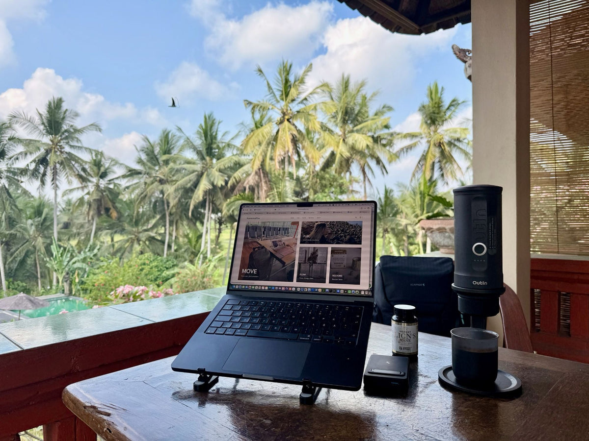 Laptop on a Scapade AirStand Pro with an OutIn espresso maker and a MagPower power bank on a terrace among palm trees