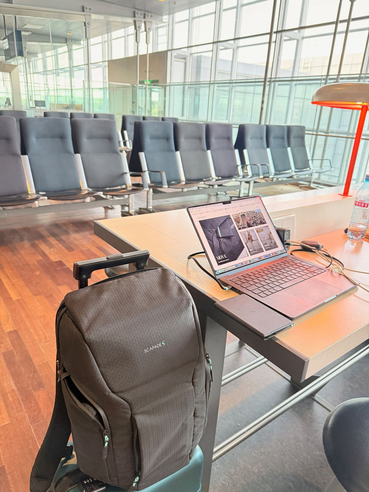 Scapades backpack and a laptop open on PureNomadFlow at an airport gate