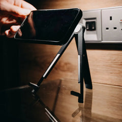 AirStand foldable stand holding a phone on a hotel-room desk